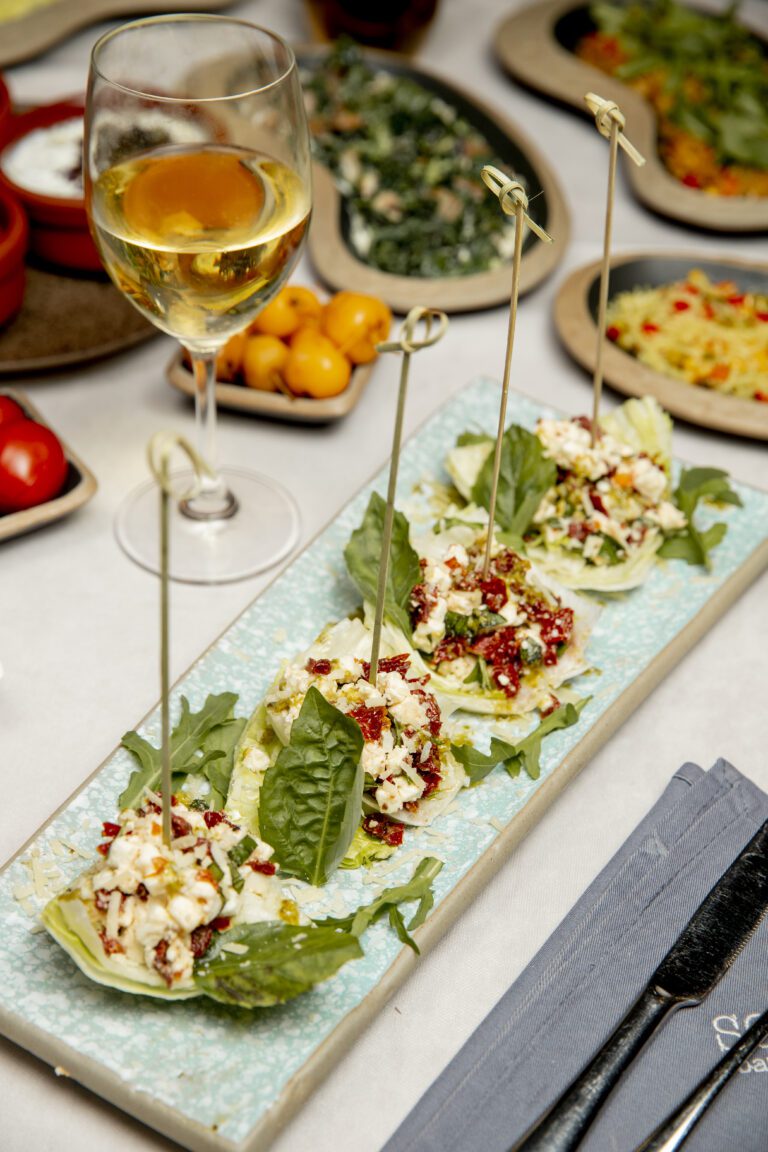 side dish with peppers grated cheese and greens served with glass of wine